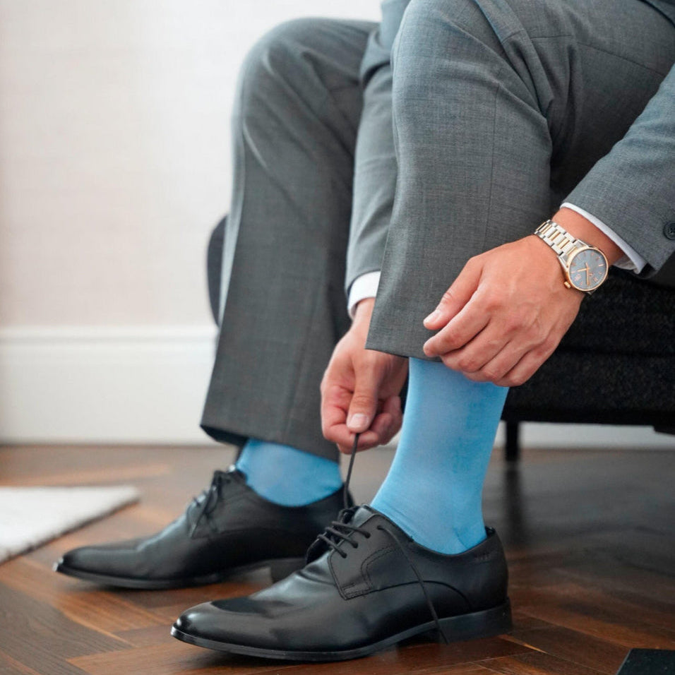 Man sitting in brown leather chair wearing blue falke socks